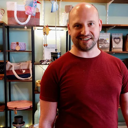 Ein junger Mann steht vor Regalen mit regionalen Lebensmittelprodukten in dem Geschäft Davids Laden 