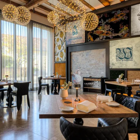 Ein elegantes Restaurant mit einer modernen Einrichtung. Große Fenster lassen viel Tageslicht herein und die Wände sind mit Kunstwerken dekoriert.