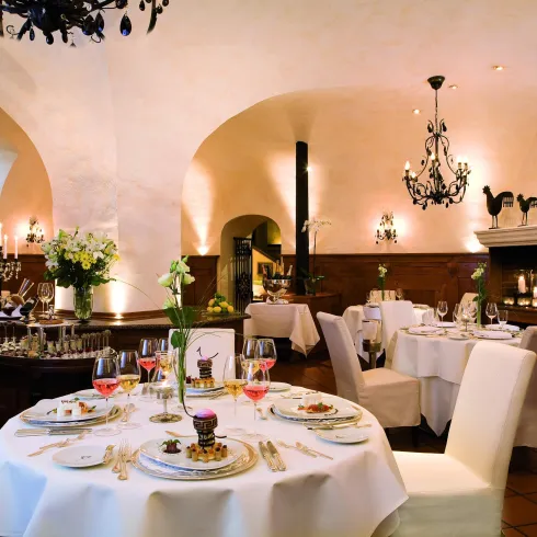 Ein elegantes Restaurant mit stilvollen Tischen und Tafeldekoration. Die warmen Farben und die beleuchteten Kronleuchter schaffen eine gemütliche Atmosphäre.