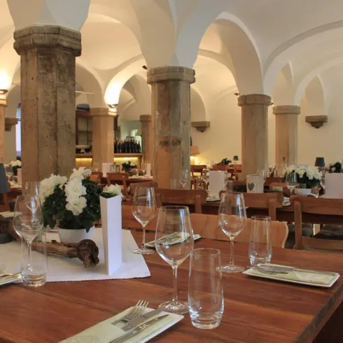 Ein stilvolles Restaurant mit Holzmöbeln und eleganten Tischgedecken. Die sanfte Beleuchtung und die hohen Decken schaffen eine einladende Atmosphäre.