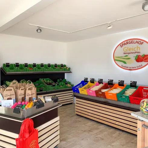 Ein Geschäft für frische Produkte mit farbigen Regalen. Es gibt verschiedene Gemüsearten und Einkaufstaschen auf den Tischen.