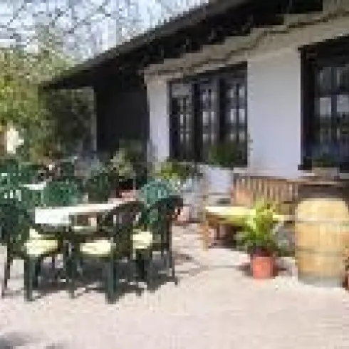 Außenbereich des Weinguts Hubach, Stühle und Tische stehen auf der gepflasterten Terasse. Das Gebäude im Hintergrund ist mit Holzakkzenten versehen.