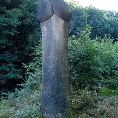 Ein großer steinerner Obelisk steht inmitten von Bäumen. Die Umgebung ist grün und natürlich.