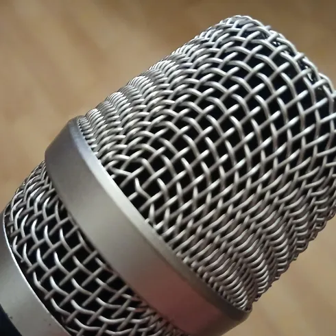 Ein nahes Bild eines Mikrofons mit einem metallenen Gitter. Die Oberfläche ist glänzend und detailliert.
