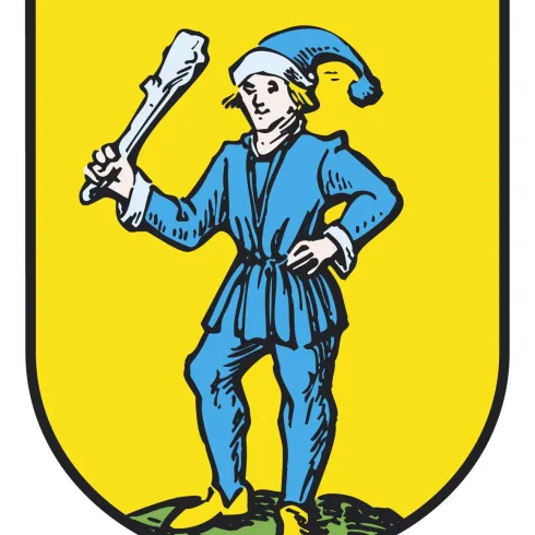 Ein Wappen mit einem Mann in blauem Gewand und einer Mütze, der einen Knochen in der Hand hält. Der Hintergrund ist gelb und der Mann steht auf einem grünen Hügel.