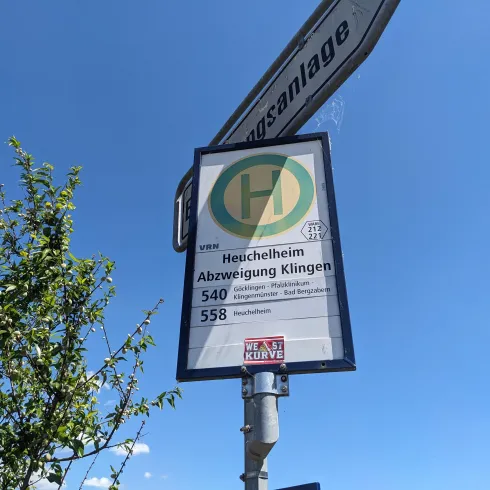 Ein Haltestellenschild mit Informationen zu den Buslinien 540 und 558. Der Himmel ist blau und klar, und es sind einige Pflanzen im Bild.