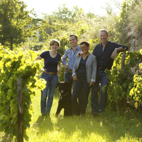 Die Bühler Familie und ihr Hund stehen zwischen den Weinreben.