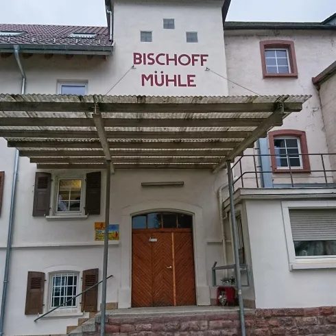 Ein historisches Gebäude mit der Beschriftung "BISCHOFF MÜHLE". Es hat eine interessante Architektur und einen einladenden Eingang.