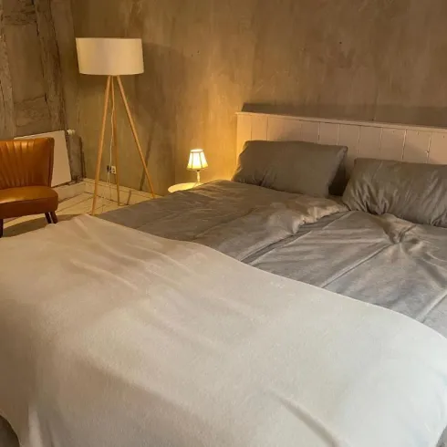 Ein modernes Schlafzimmer mit einem großen Bett und einer gemütlichen Atmosphäre. Eine Lampe und ein Sessel runden den Raum ab.