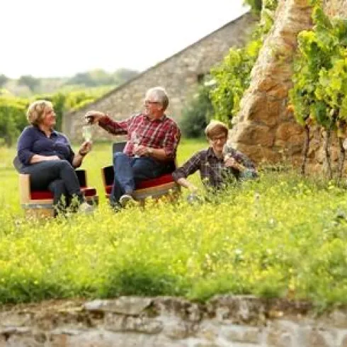 Fam. Bohnenstiel sitzend in den Weinbergen mit einem Glas Wein.