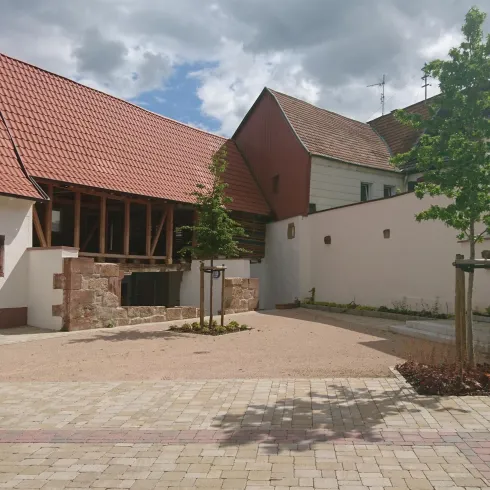 Ein schöner Innenhof mit modernen und traditionellen Gebäuden. Bäume und gepflasterte Flächen verleihen ihm eine einladende Atmosphäre.