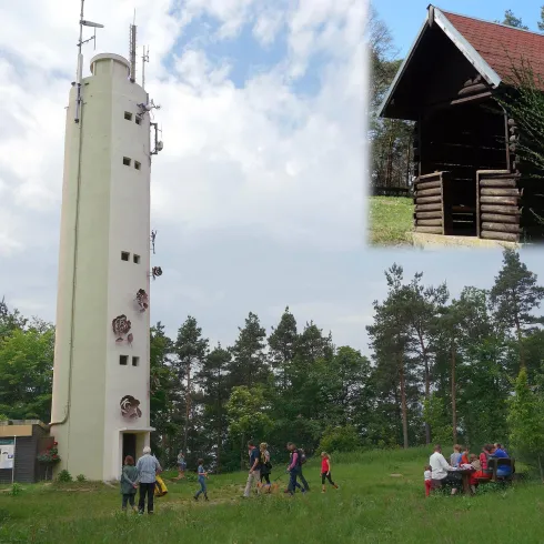 Ein Aussichtsturm inmitten von Bäumen, umgeben von einer Gruppe von Menschen. Im Bildausschnitt ist ein kleines Häuschen zu sehen.