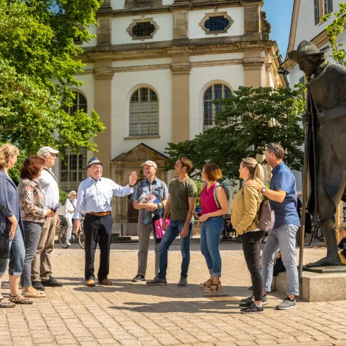 Gruppe von menschen steht bei einer Pilgerstatue in Speyer