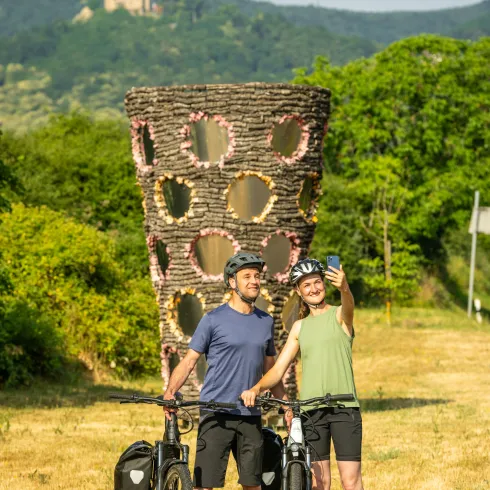 Zwei Radfahrende stehen vor der Dubbeglas Statur vor dem Hambacher Schloß 