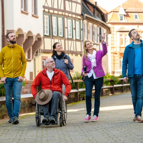 Menschen auf einer Gästeführung in einer Innenstadt mit Fachwerkhäusern.