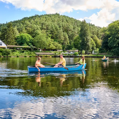 Eine Familie fährt mit einem Ruderboot über einen Weiher.
