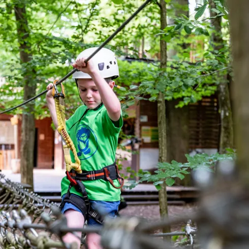Ein Kind klettert entlang eines Pfades im Kletterpark.