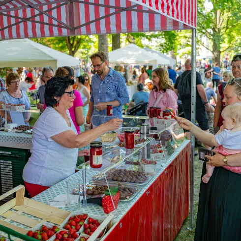 Eine Person kauft auf dem Erdbeermarkt in Herxheim bei Landau Erdbeeren von einem Erdbeerstand.