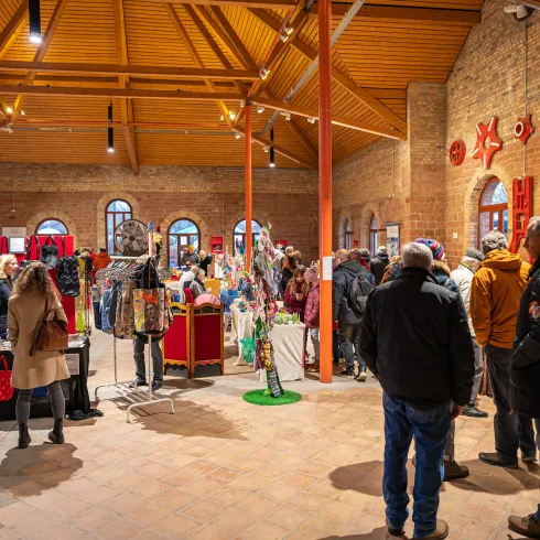 Menschen besuchen einen Weihnachtsmarkt in einem alten Gebäude.