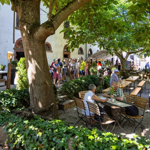 Gäste sitzen im Restaurant in Niefernheim, im Hintergrund sind Besuchende der Kunst-und Weinveranstaltung Zauberhaftes Zellertal.