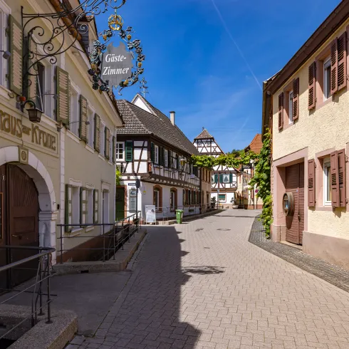 Historischer Ortskern in St. Martin. Auf einem der Fachwerkhäuser steht in goldener Schrift "Gästehaus".
