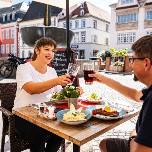 Zwei Personen sitzen im Außenbereich eines Restaurants und genießen typisch pfälzische Küche.