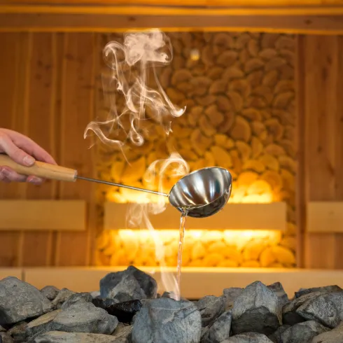 Eine Sauna, in der ein Aufguss durchgeführt wird, mit dampfender Luft und entspannender Atmosphäre.