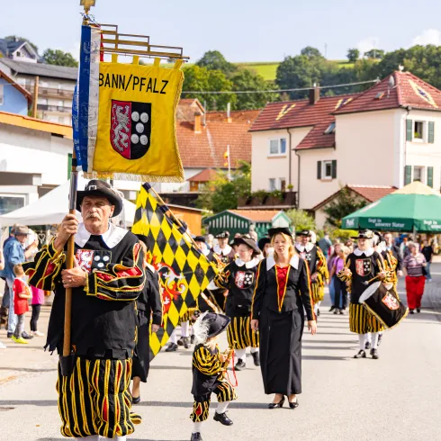 Menschen in traditioneller Kleidung laufen auf dem Sickinger Grumbeere-Markt in Wallhalben bei einer Parade mit.
