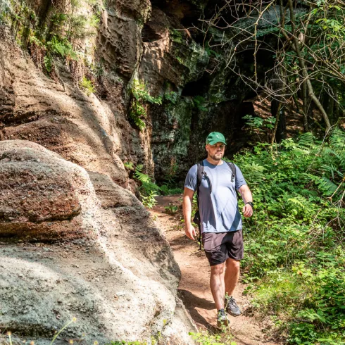 Eine Person wandert entlang eines imposanten Sandsteinfelsens im Pfälzerwald.