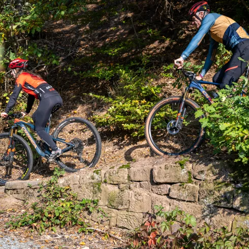 Zwei Personen fahren mit dem Mountainbike über alte Pfade im Mountainbikepark Pfälzerwald