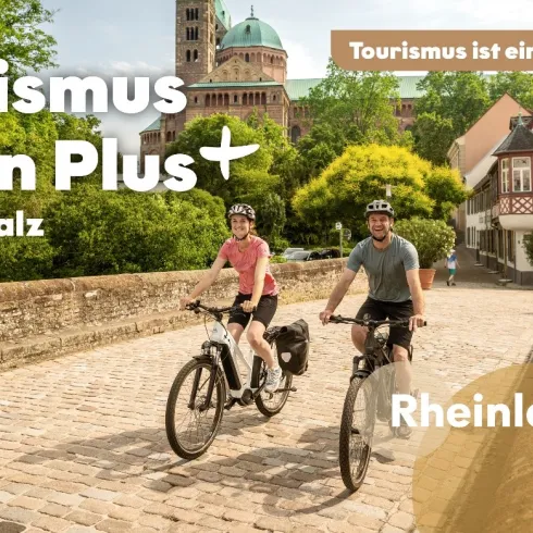Zwei Personen fahren mit dem Rad über eine Brücke nahe des Speyerer Doms. Der Bildtext lautet: Tourismus ist ein Plus für die Pfalz - Rheinlandpfalz Gold