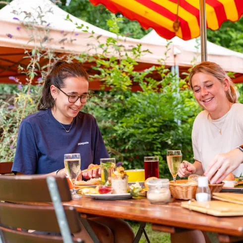 Zwei Personen sitzen an einem Tisch im Außenbereich des Obsthof Wicke und genießen regionale Kost.