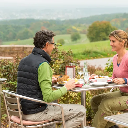 Zwei Personen sitzen an einem Tisch im Außenbereich eines Restaurants und genießen regionale Speisen.