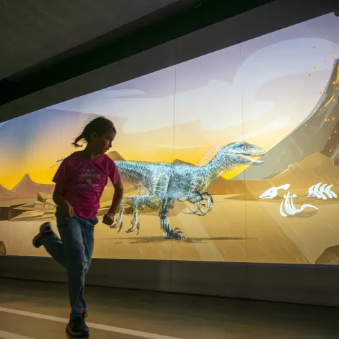 Ein Kind rennt an einem großen Bildschirm - Teil der interaktiven Ausstellung des Dynamikums entlang. 