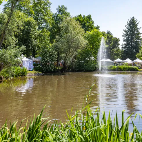 Die Ausstellerzelte der Bellheimer Gartentagen stehen entlang des Ufers eines Teiches.