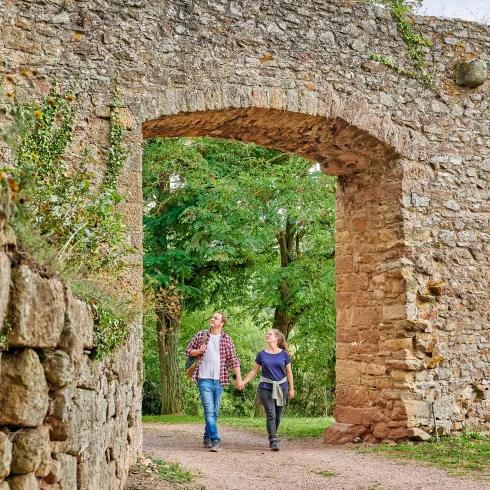 Zwei Personen wandern durch ein Torbogen bei der Moschellandsburg.