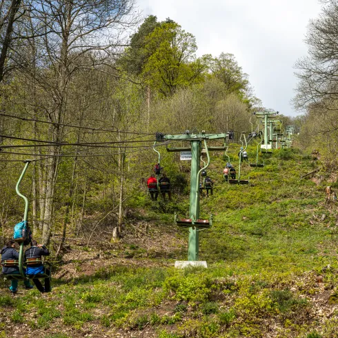 Personen sitzen in den Liftsesseln der Rietburgbahn in Edenkoben