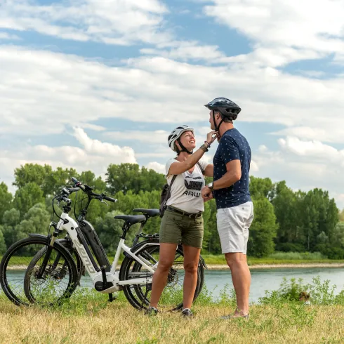Zwei Personen stehen mit ihren Rädern am Rhein.