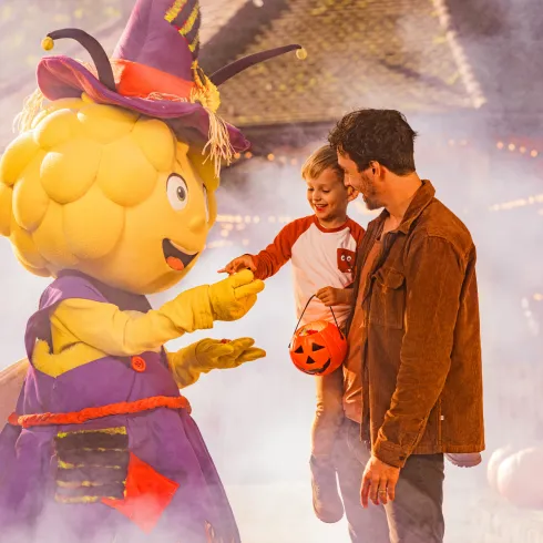 Das Maskottchen der Biene Maia unterhält sich mit Besuchenden des Freizeitparks.