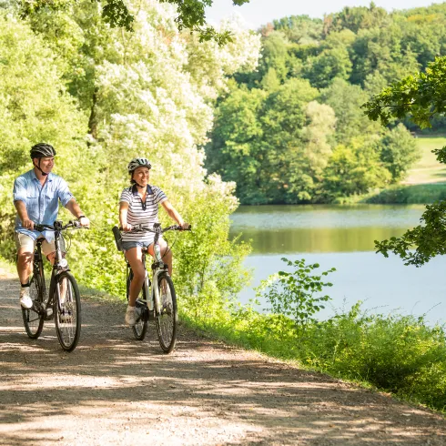 Zwei Personen fahren mit dem Rad im Sommer vorbei am Ohmbachsee