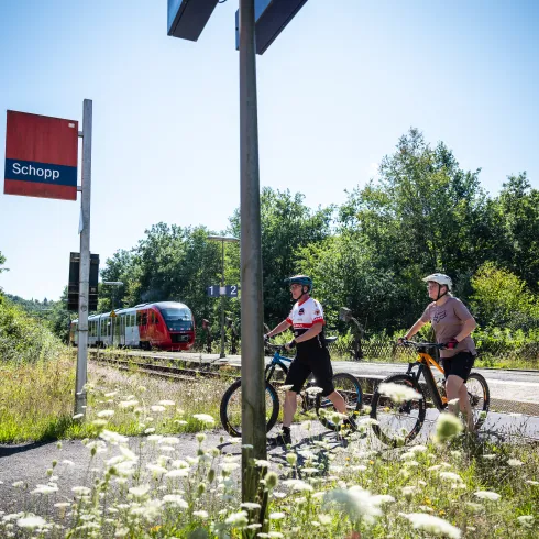 Zwei Personen mit ihren Mountainbikes am Bahnhof Schopp. 
