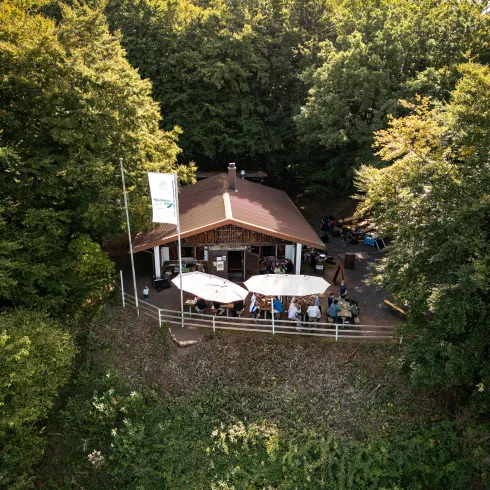 Menschen sitzen im Außenbereich der Hohlsteinhütte und genießen ein Gericht und etwas zu Trinken. 