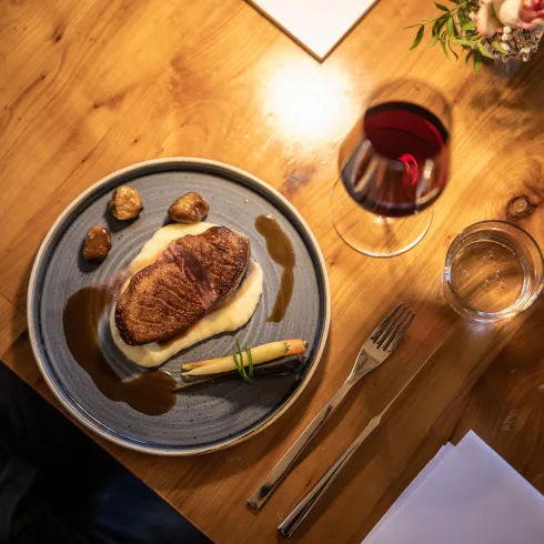 Ein Fleischgericht auf einem Teller und ein Glas Rotwein beim Gasthaus Kollektur im Zellertal